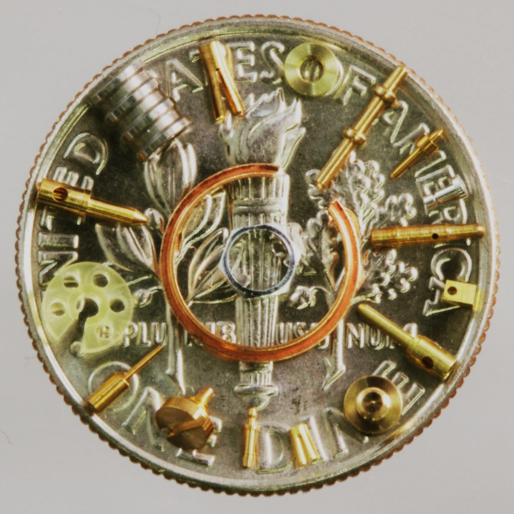 Many small parts on a dime, showing the scale of our micro-machining